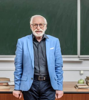 smiling-grey-hair-professor-standing-in-lecture-ro-2022-12-16-17-25-04-utc.jpg